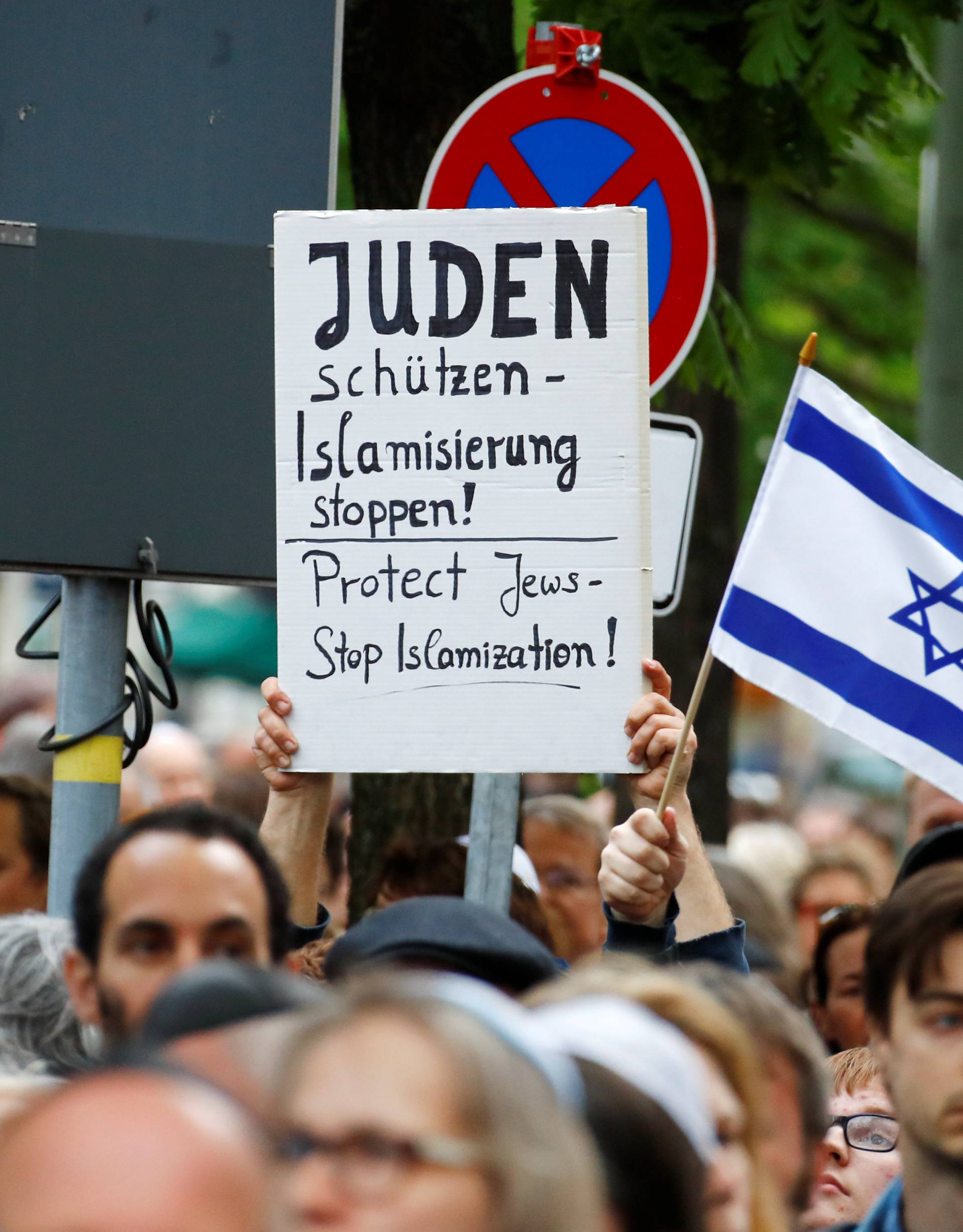 People hold a sign and Isreali flag as they attend a demonstration in front of a Jewish synagogue in Berlin