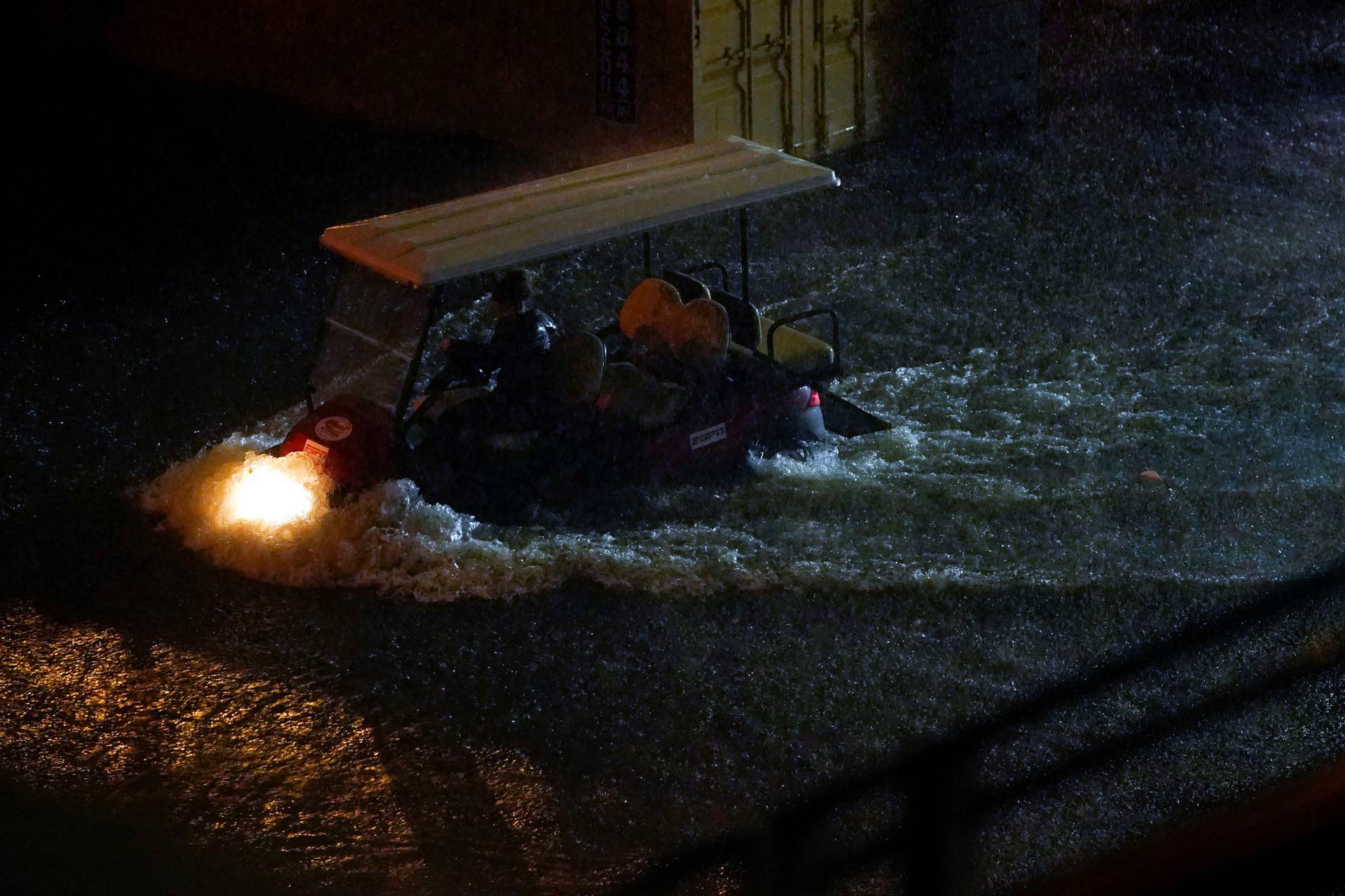A golf cart drives through flood water outside Louis Armstrong Stadium