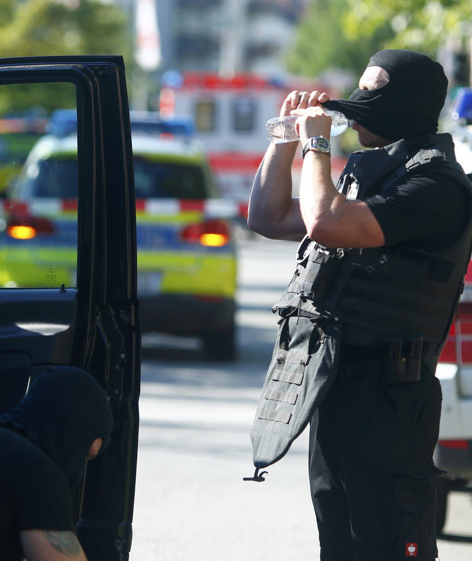 A German policeman drinks near a cinema complex after a masked man with a gun and ammunition belt opened fire in Viernheim