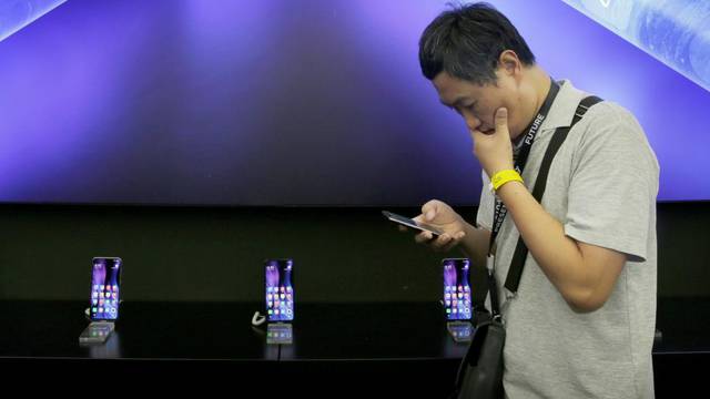 A journalist stands next to a poster of Xiaomi Mi MIX Alpha surround display 5G concept smartphone in Beijing