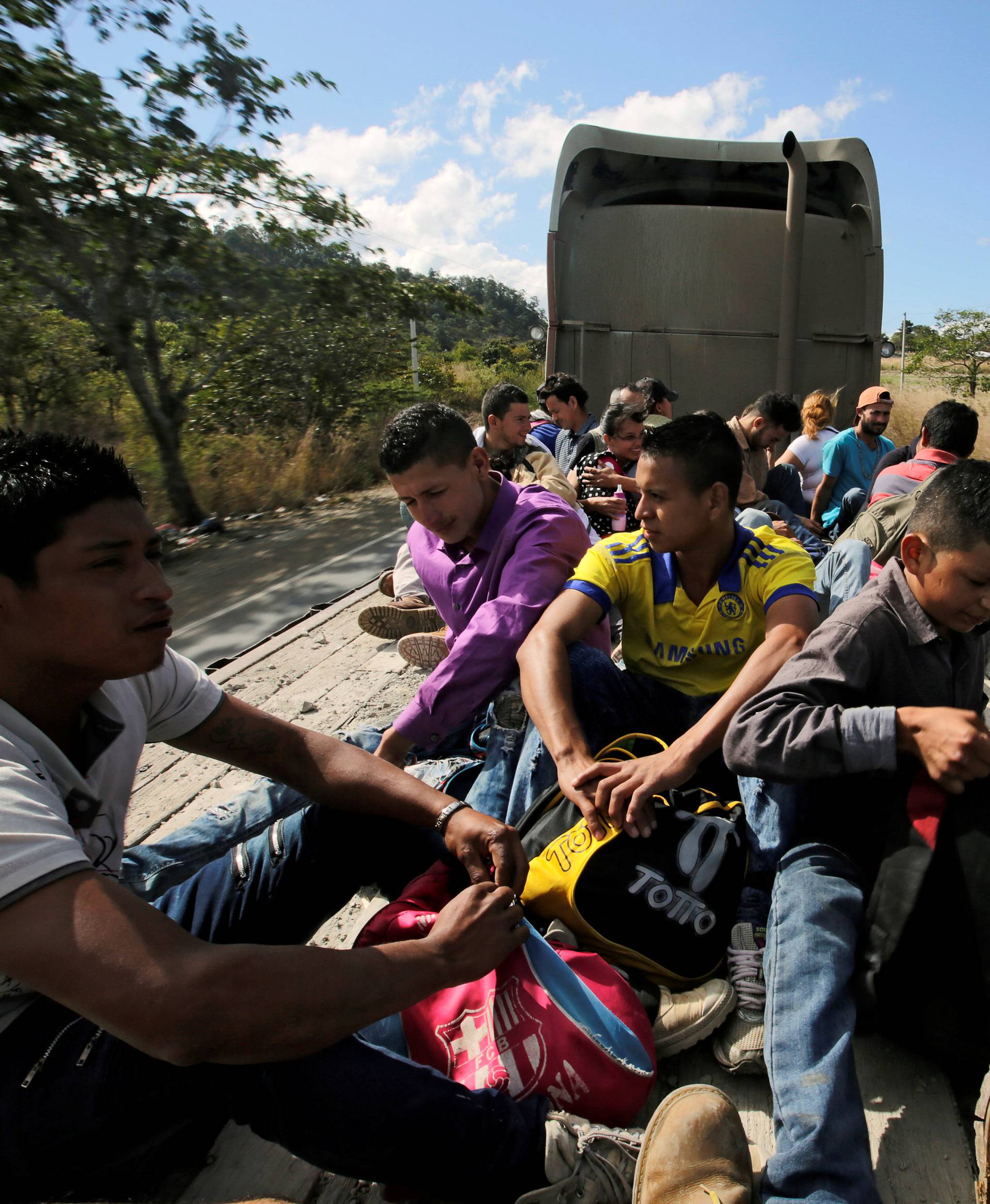 Hondurans, part of a new caravan of migrants travelling towards the United States, ride in a trailer as they hitch a ride in Cucuyagua
