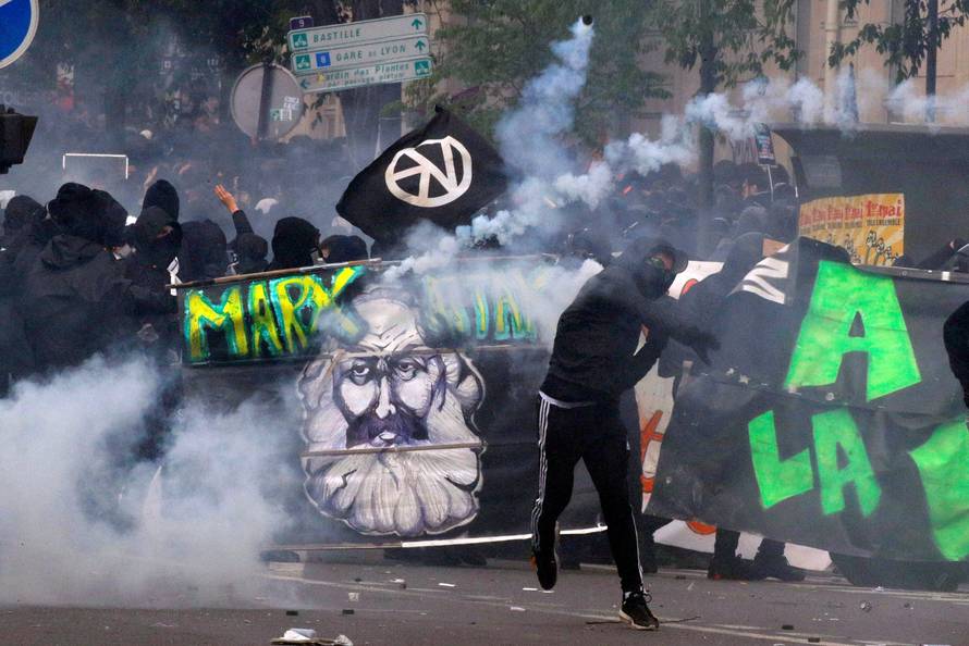 Tear gas floats around masked protesters during clashes with French CRS riot police at the May Day labour union rally in Paris