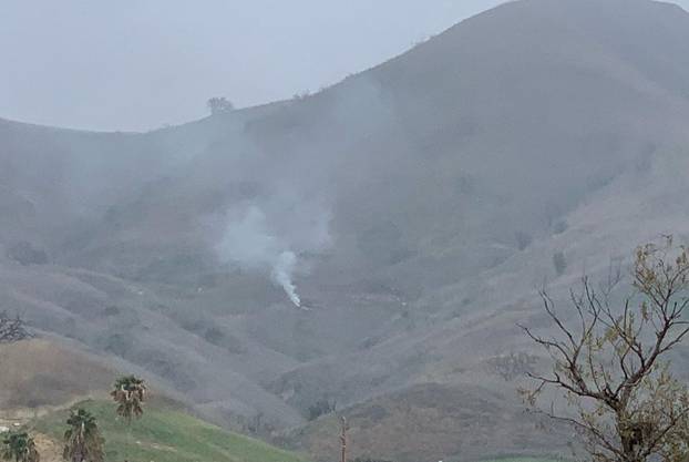 Smoke rises amid foggy weather from the site of a helicopter crash that killed former NBA star Kobe Bryant along a hillside in Calabasas