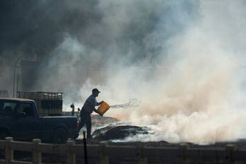 A rancher does what he can to try and put out flames after the Lilac Fire, a fast moving wild fire, came through Bonsall, California