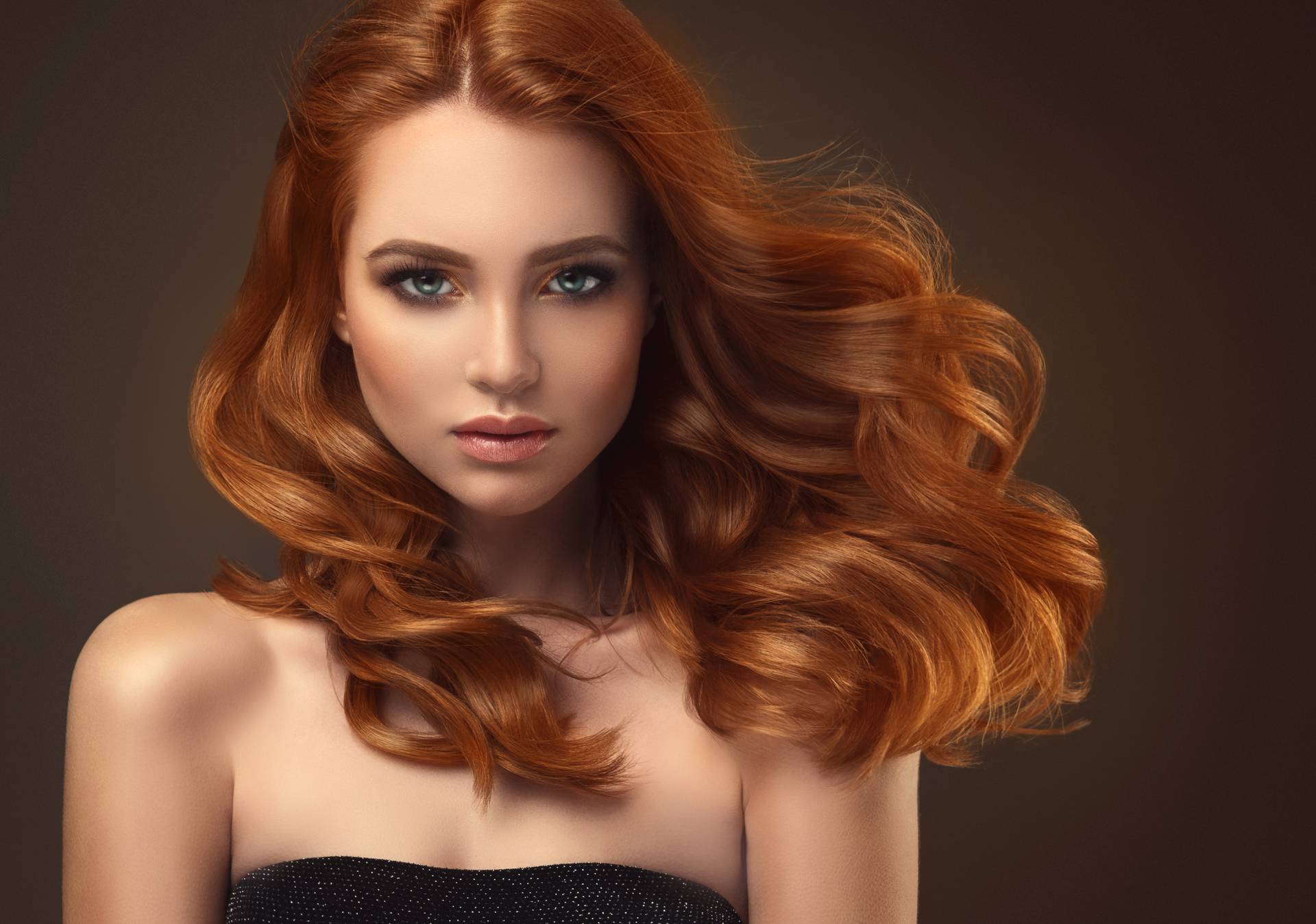 Red haired woman with voluminous, shiny and curly hairstyle.Flying hair.