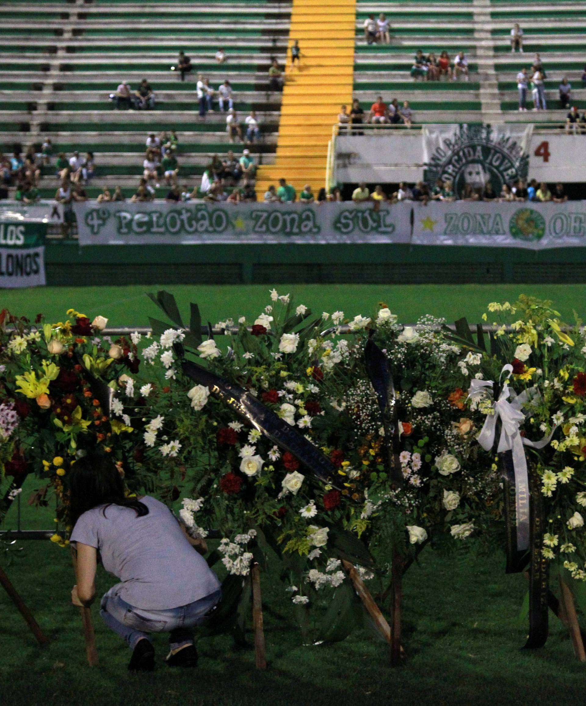 A woman places flowers before a mourning ceremony for victims after a plane carrying Brazil's soccer team Chapecoense crashed in Colombia, at Arena Conda stadium in Chapeco