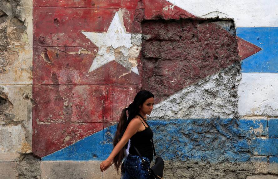 A woman walks in front of a mural of the Cuban flag in Havana, Cuba