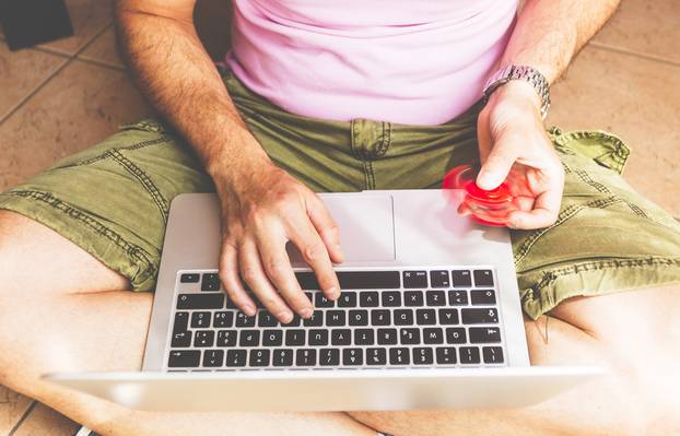 Young,Adult,Man,Seated,On,A,Floor,,Working,On,Laptop