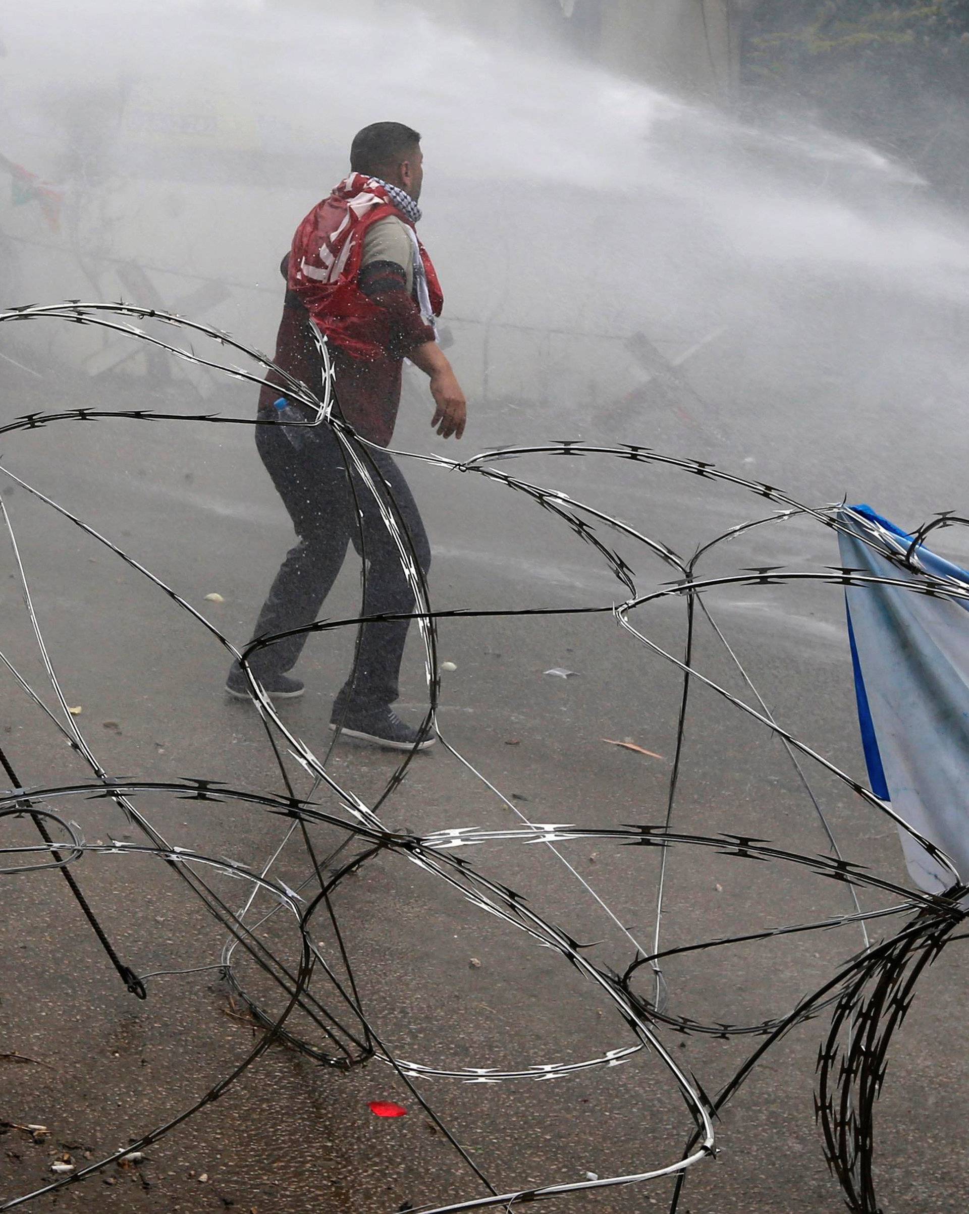 Protesters are sprayed with water near the U.S. embassy in Awkar east of Beirut