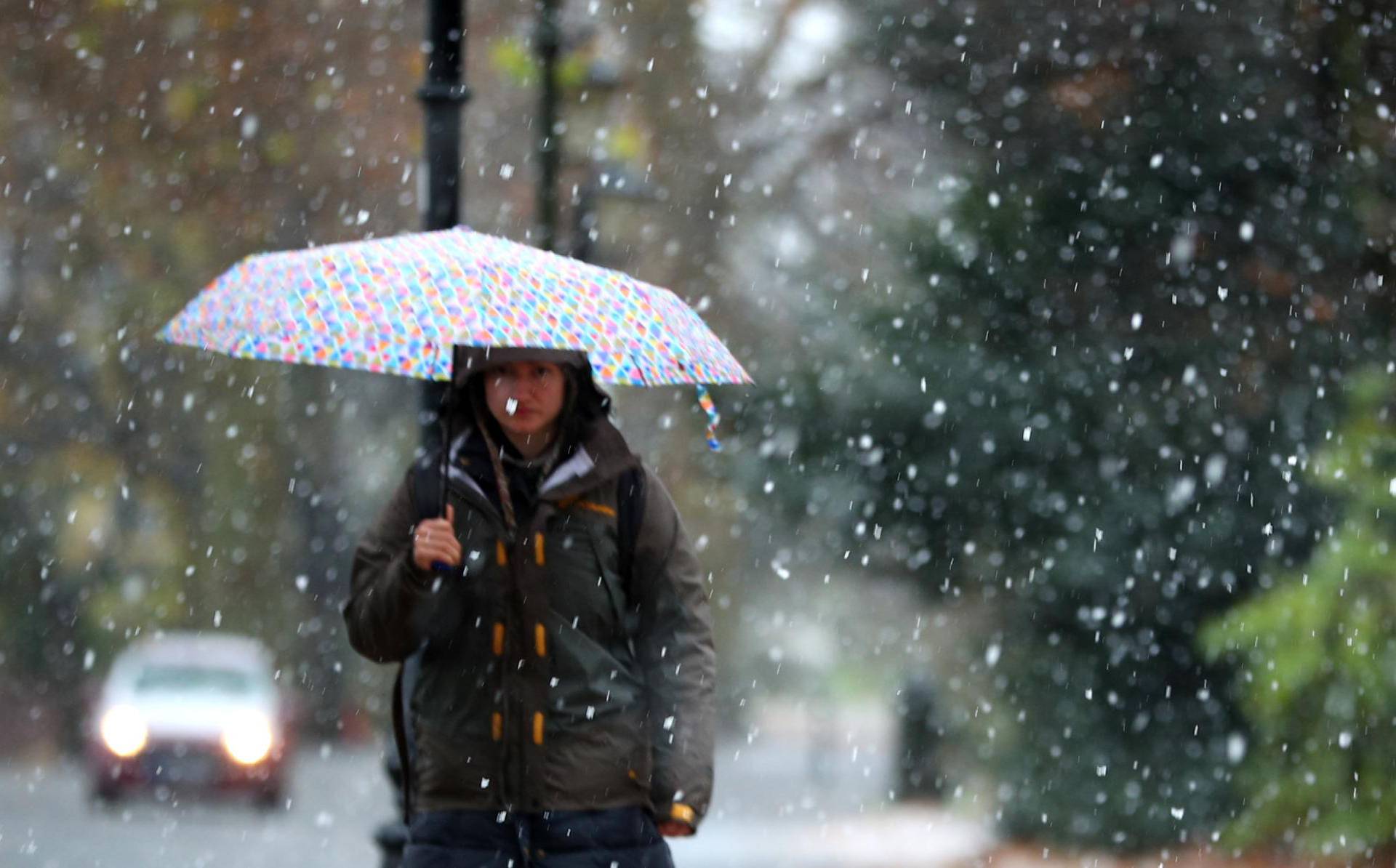 A woman walks through the snow in Battersea Park, London