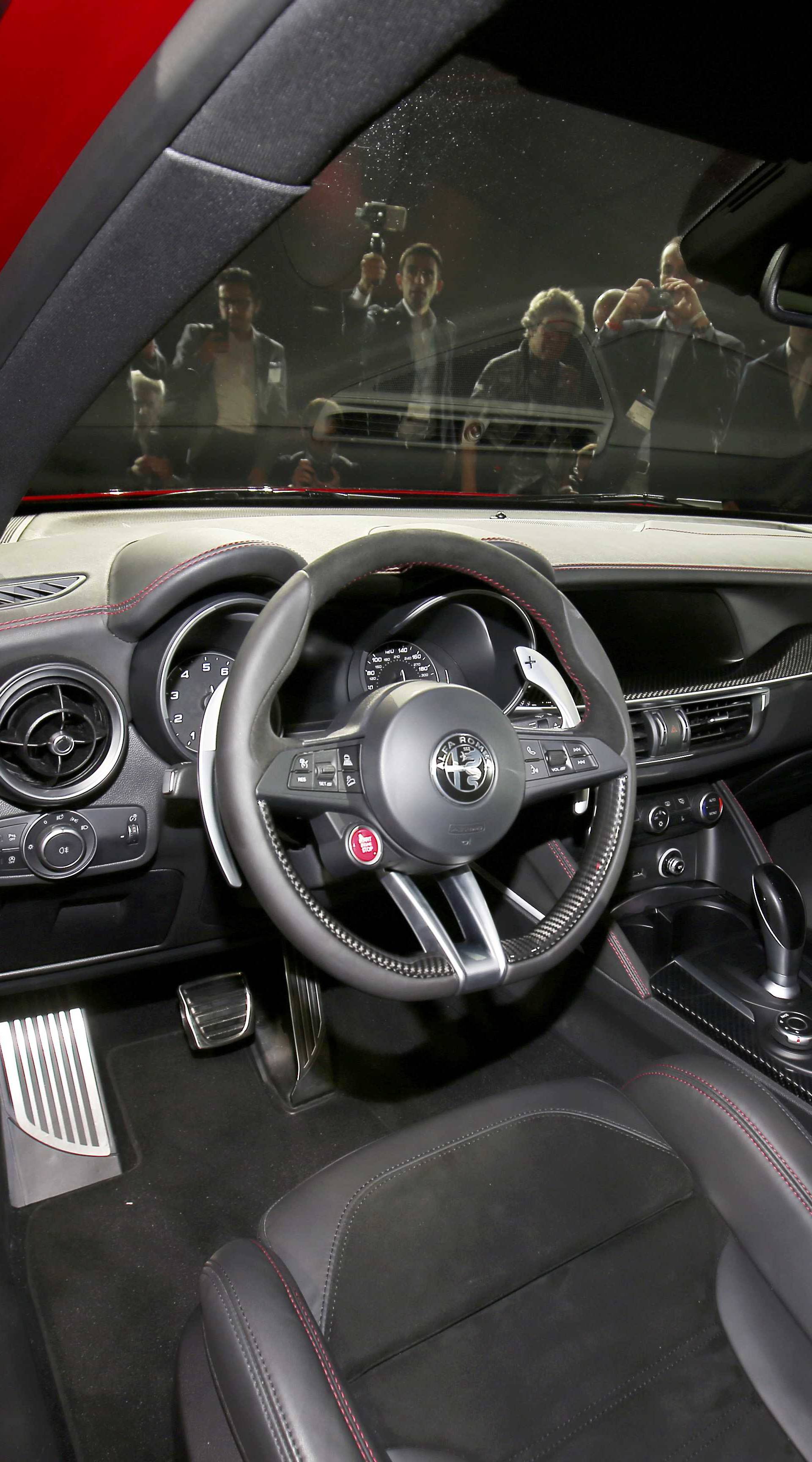People look over the interior of the car as Alfa Romeo introduces the 2018 Stelvio SUV at the 2016 Los Angeles Auto Show in Los Angeles
