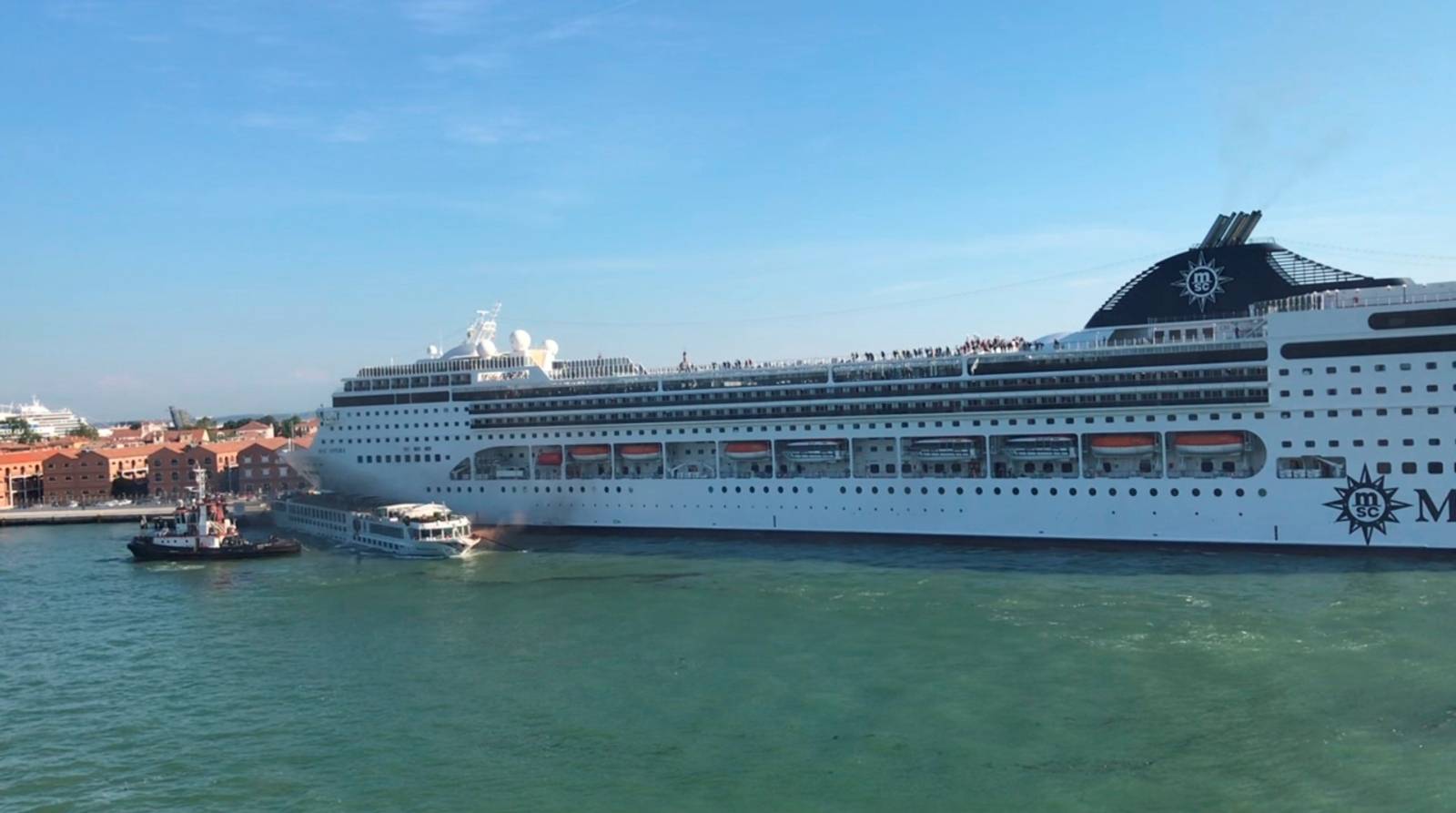 A huge cruise ship MSC Opera crashes into a dock and a tourist riverboat on a busy canal in Venice