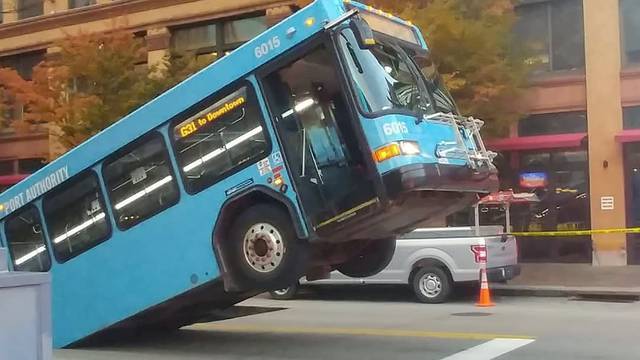 Front of a public bus sticks out of a sinkhole on 10th and Penn Avenue in Pittsburgh