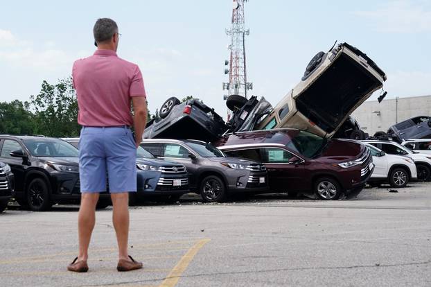 A man looks at wrecked trucks at a Toyota dealer following a tornado in Jefferson City