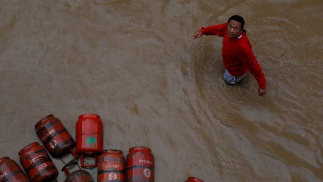 FILE PHOTO: A man walks past gas cylinders in a flooded colony in Kathmandu