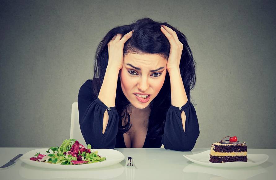 Woman tired of diet restrictions deciding to eat healthy food or cake she is craving