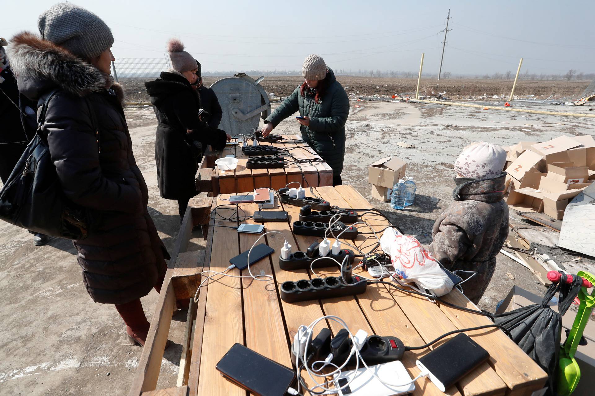 People stand in a line during the distribution of humanitarian aid in the besieged city of Mariupol