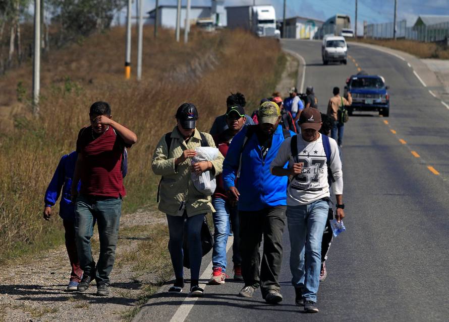 Hondurans, part of a new caravan of migrants travelling towards the United States, walk along a road in Cucuyagua