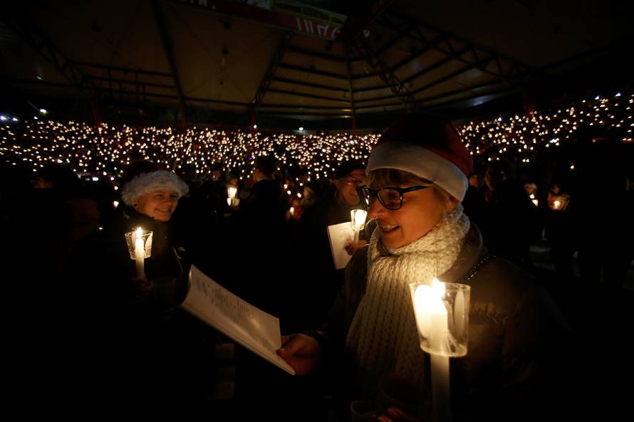 People attend the "Weihnachtssingen", a candle-lit carol concert at the Alte Foersterei stadium in Berlin