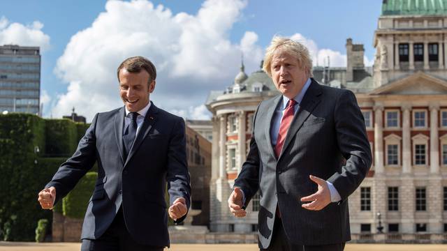 British Prime Minister Boris Johnson and French President Emmanuel Macron react after watching The Red Arrows and La Patrouille de France perform a flypast, at Horse Guards Parade in London
