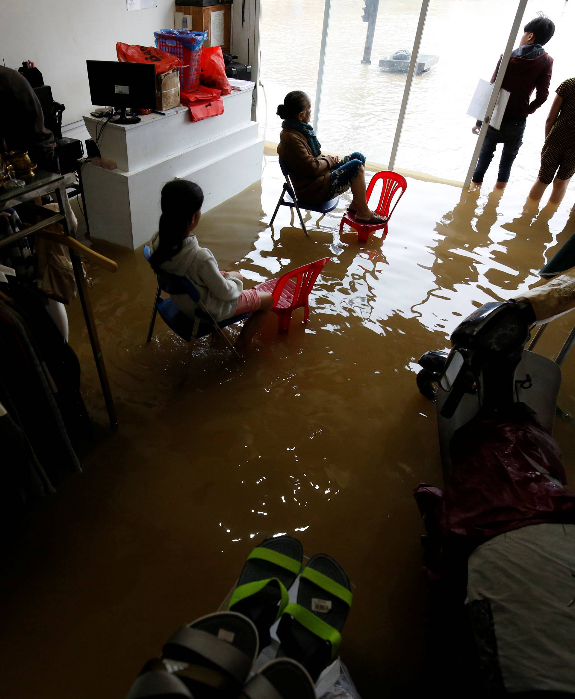 Residents sit on their flooded fashion shop after typhoon Damrey hits Vietnam in Hue city