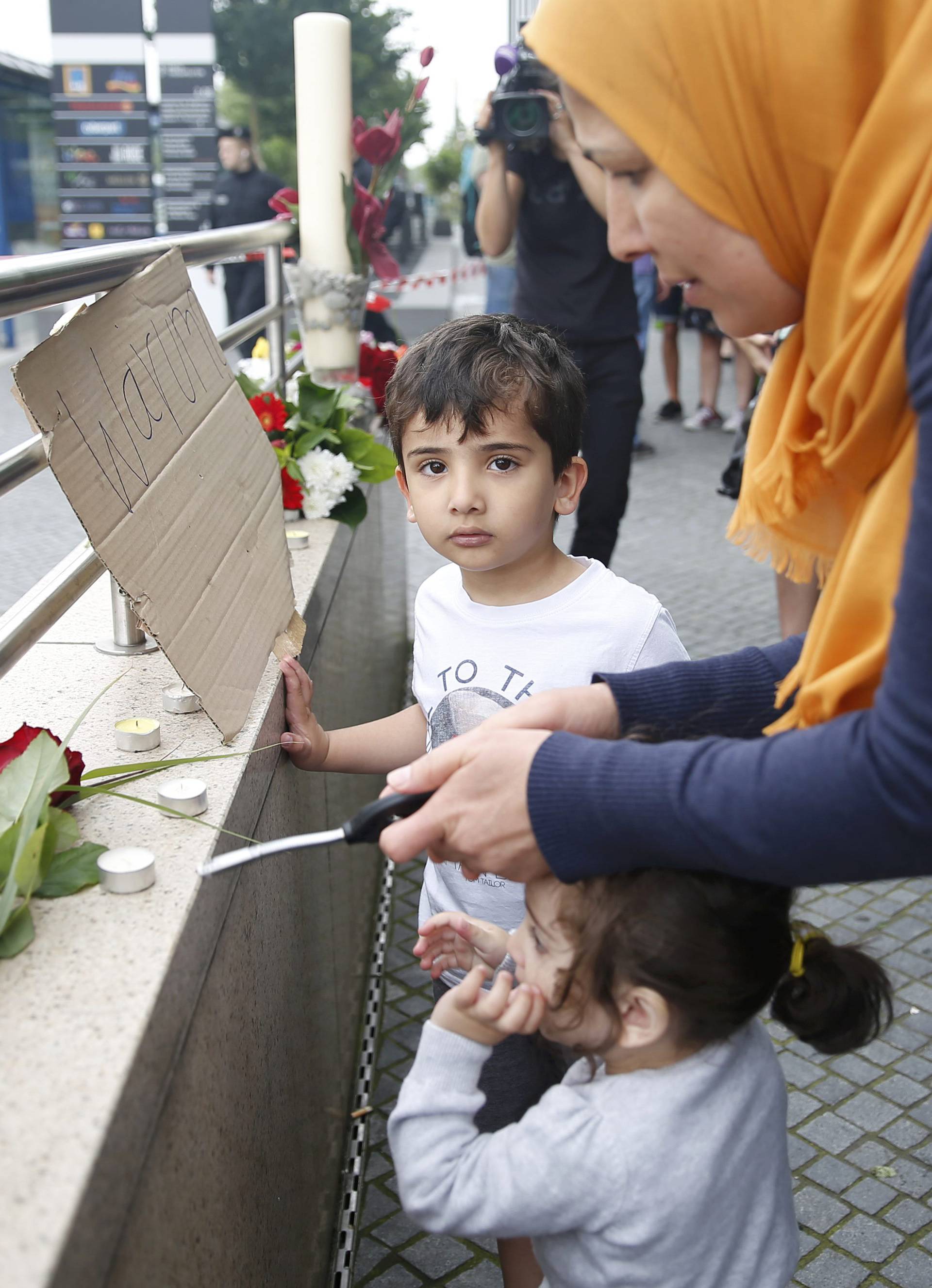 Woman lights candles on wall near Olympia shopping mall in Munich