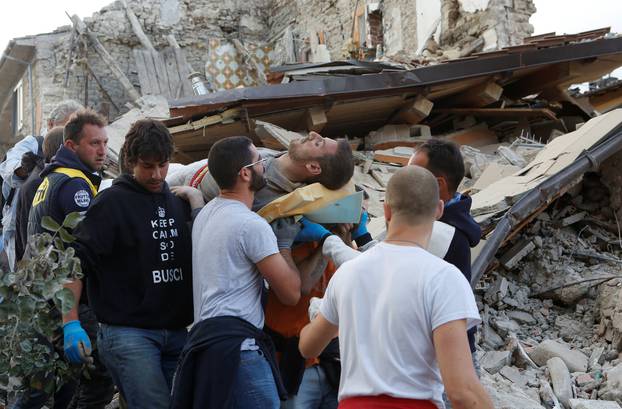 A man is carried away after been rescued alive from the ruins following an earthquake in Amatrice