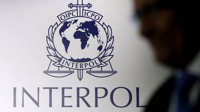 FILE PHOTO: A man passes an Interpol logo during the handing over ceremony of the new premises for Interpol's Global Complex for Innovation in Singapore