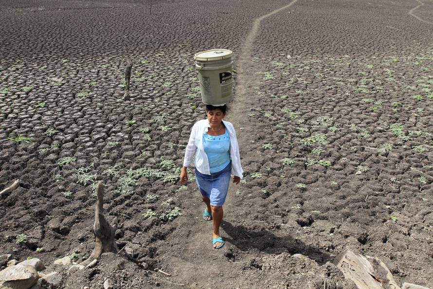 A woman carries a bucket of water on her head at Santa Isabel  town.