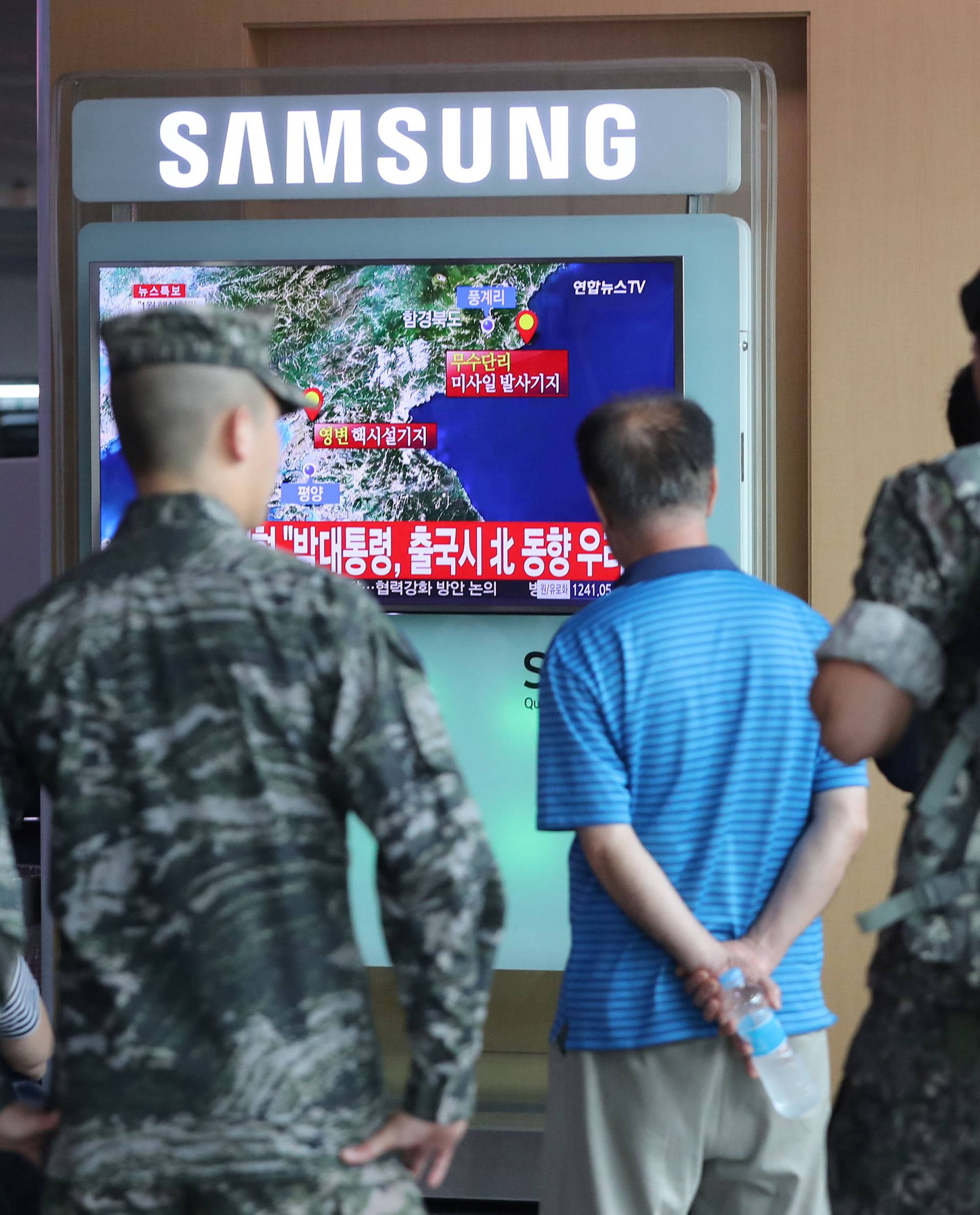 South Korean soldiers and passenger watch a TV broadcasting a news report on Seismic activity produced by a suspected North Korean nuclear test, at a railway station in Seoul