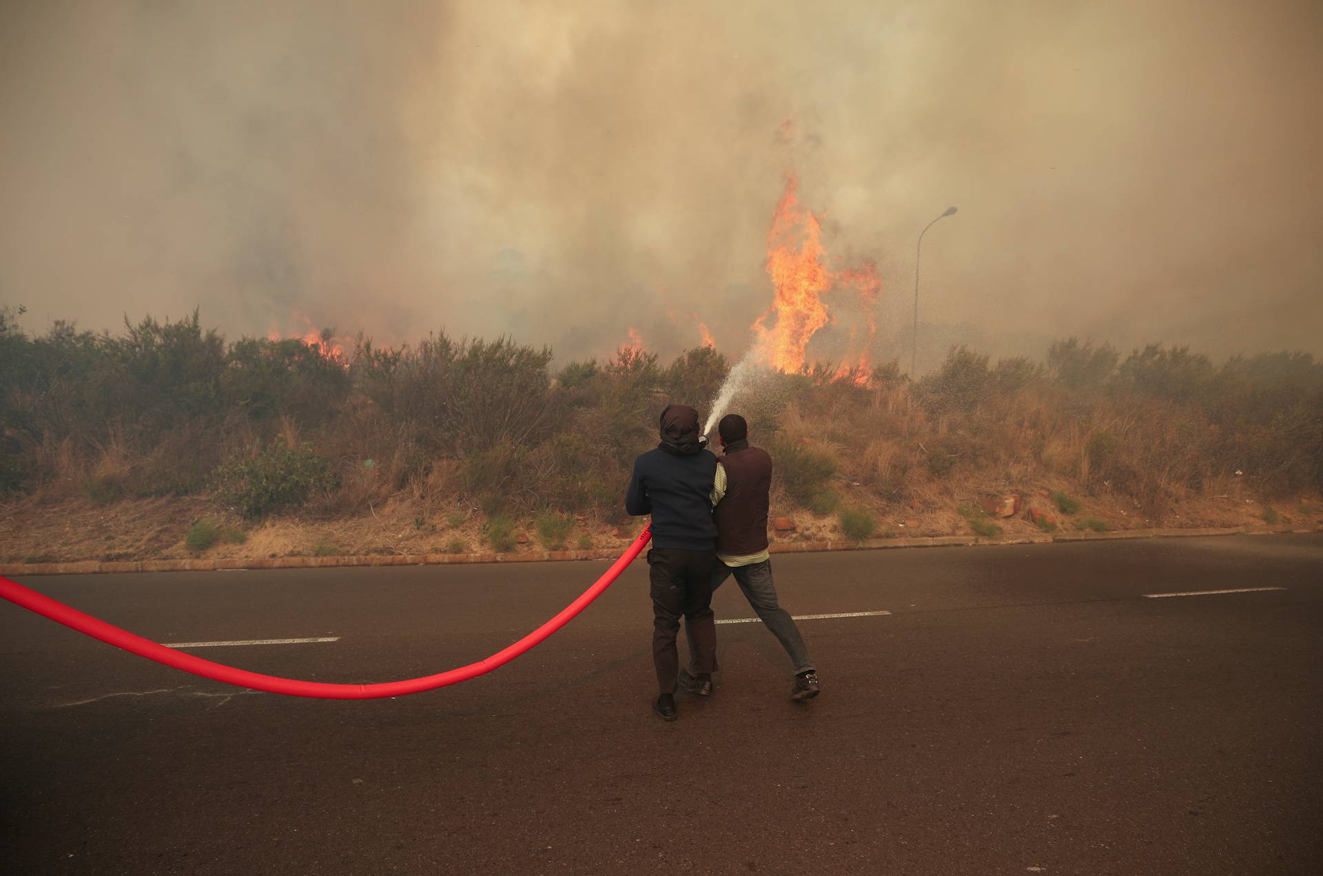 Firefighters and residents battle to contain a fire fanned by strong winds on the slopes of Table Mountain in Cape Town