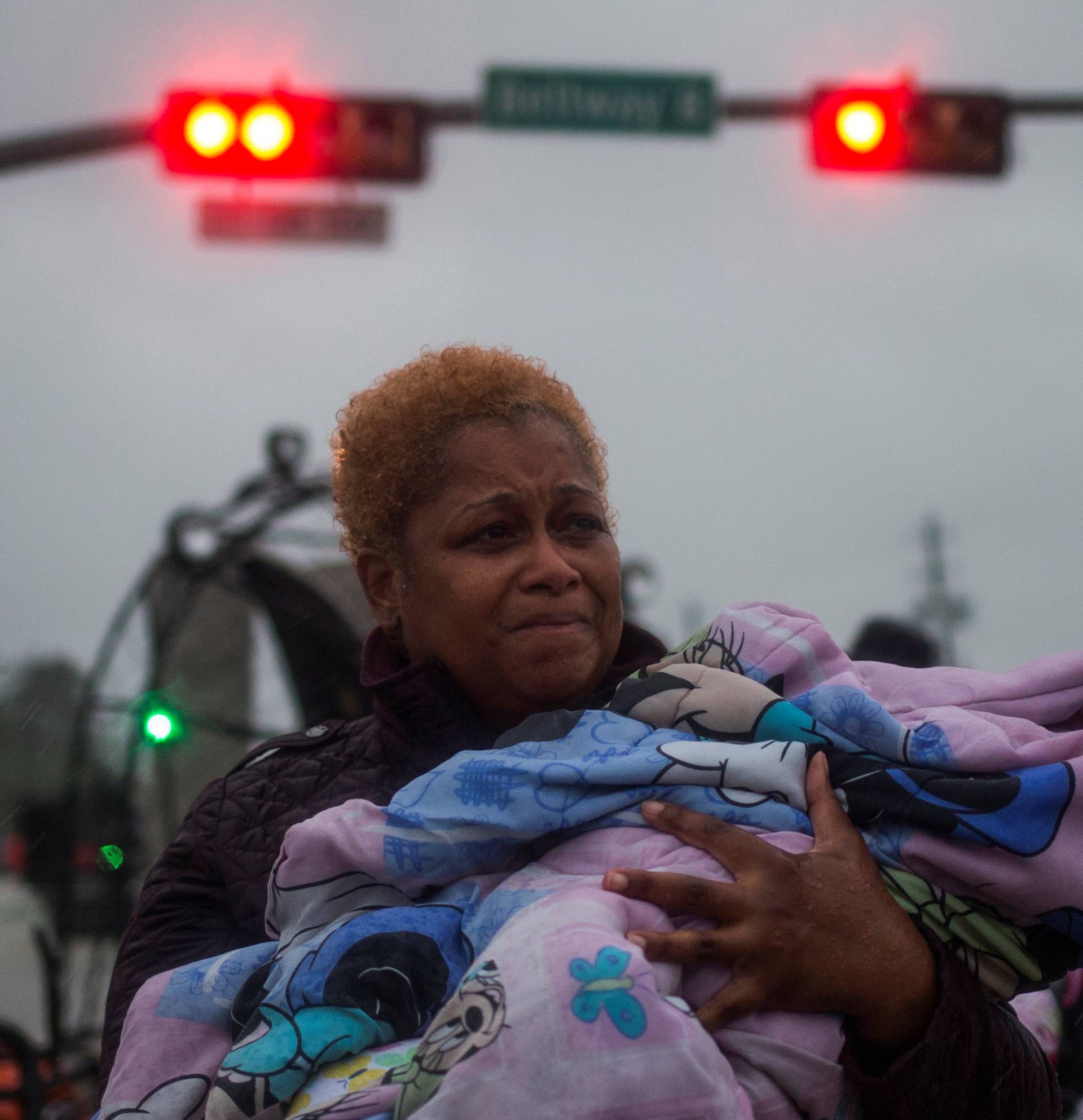 A woman holds her child after arriving to high ground due to floods caused by Tropical Storm Harvey along Tidwell Road in east Houston