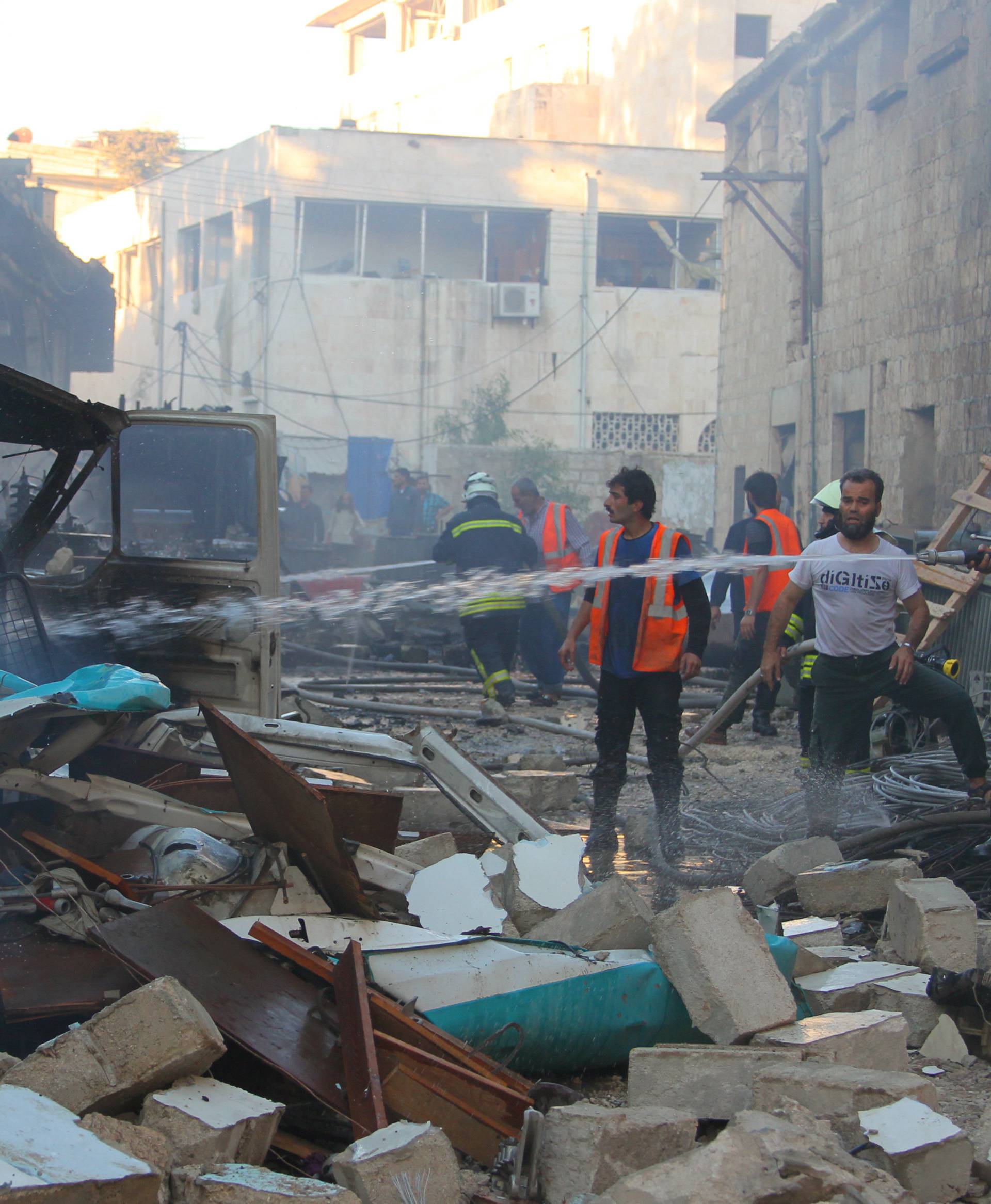 Civil defence members put out a fire at a site hit by airstrikes in Idlib