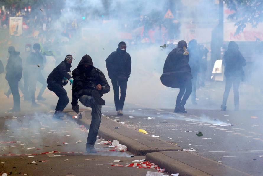 Tear gas floats around masked protesters during clashes with French CRS riot police at the May Day labour union rally in Paris