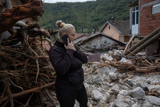 A woman talks on a mobile among debris following a landslide in the flooded village of Donja Jablanica