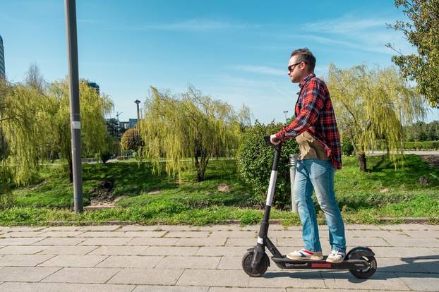 Side,View,Of,Man,Riding,E-scooter,On,Pavement,Surface,In
