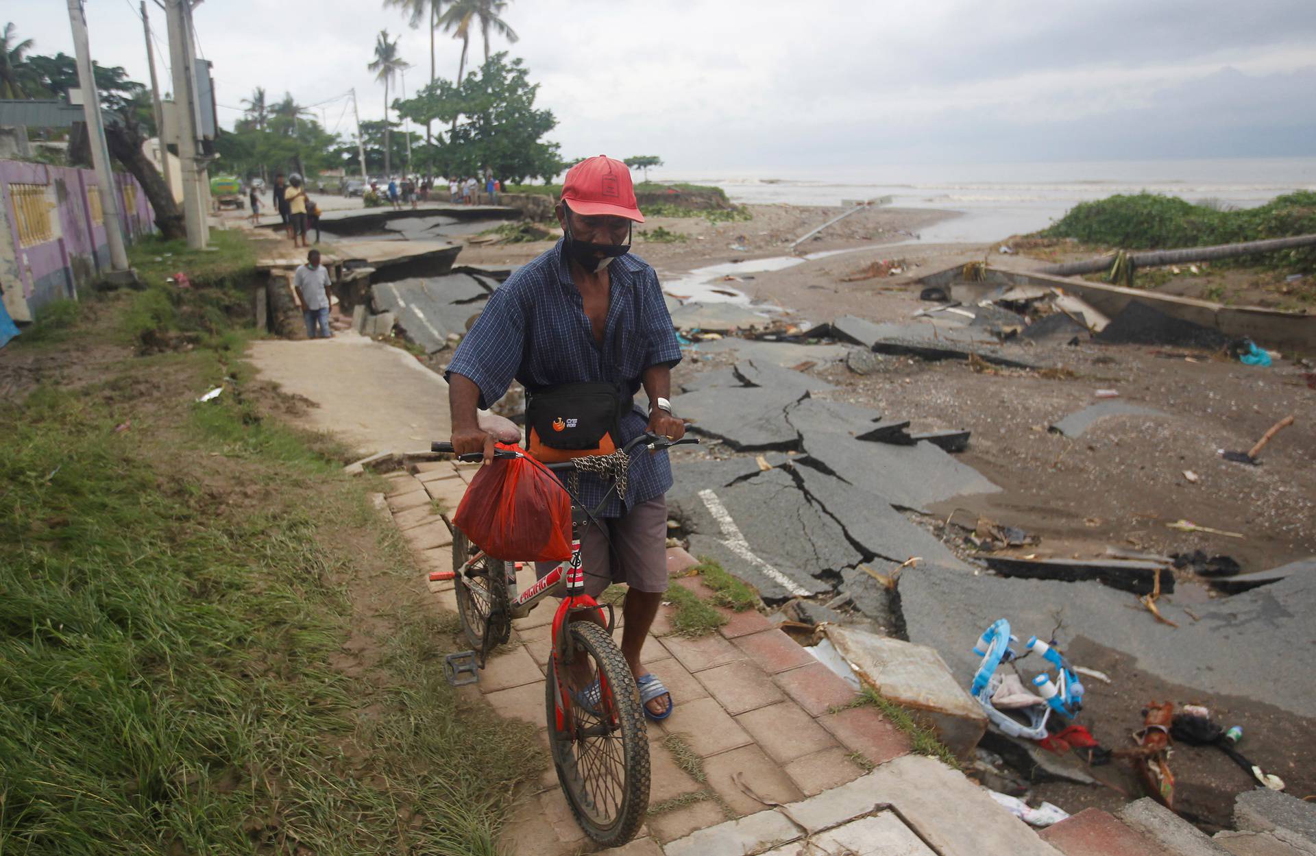 A man wheels his bicycle through roads damaged by floods after heavy rains in Dili