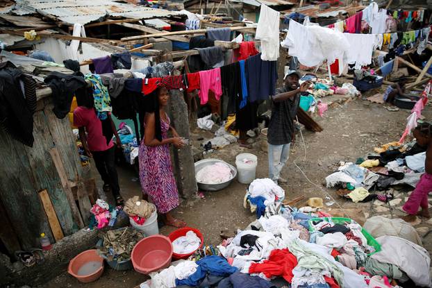 People wash their clothes in front of their partially destroyed houses after Hurricane Matthew passes Jeremie