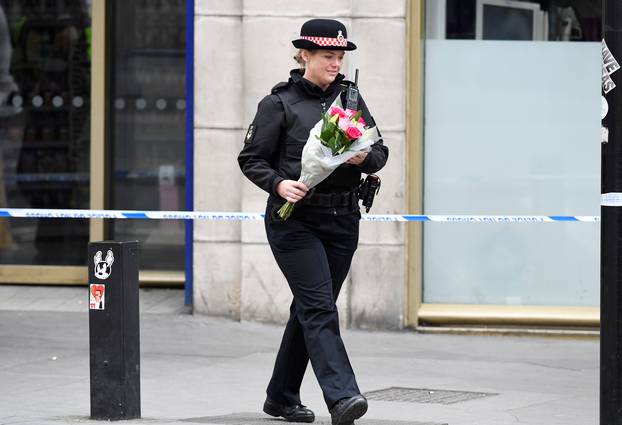 A police woman carries flowers near London Bridge after an attack left 7 people dead and dozens injured in London