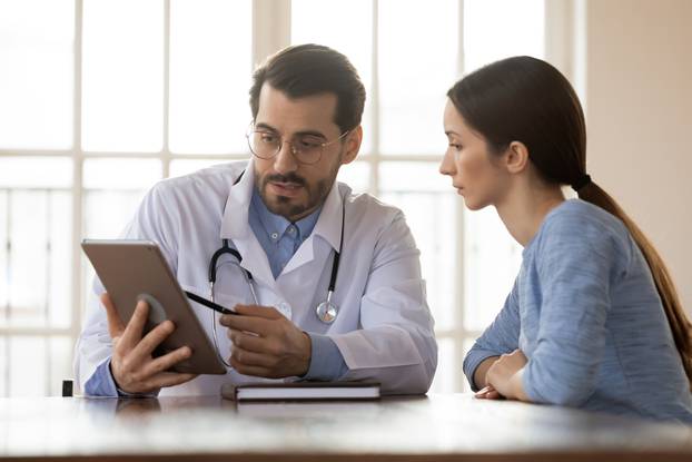 Focused,Young,Male,Doctor,Pointing,At,Digital,Computer,Tablet,Screen,