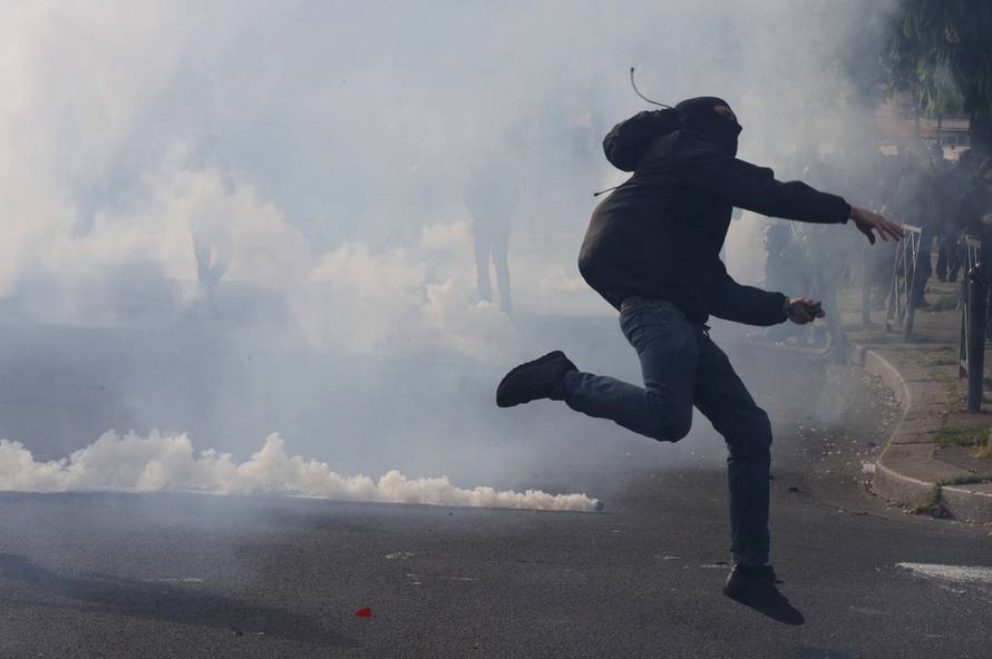 A masked youth runs through a cloud of tear gas during clashes with gendarmes and police during a demonstration against the French labour law proposal in Paris