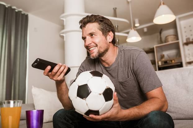 Young,Soccer,Fan,Man,Watching,Football,Game,On,Television,At