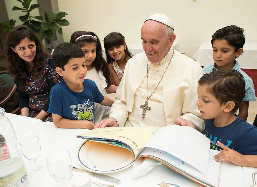Pope Francis sits with some Siryans refugees at the Vatican 