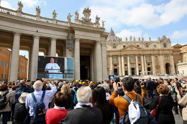 People watch Pope Francis makes first public appearance in five weeks, on a big screen in St. Peter's Square at the Vatican