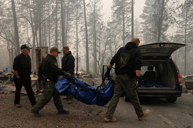 Yuba and Butte County Sheriff deputies carry a body bag with a deceased victim during the Camp fire in Paradise