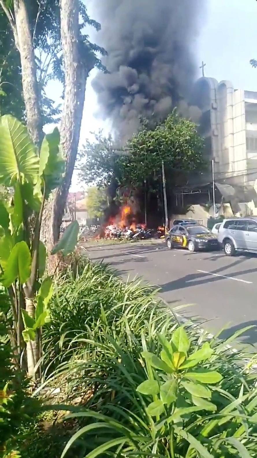 Smoke billows from burning debris at a church in Surabaya