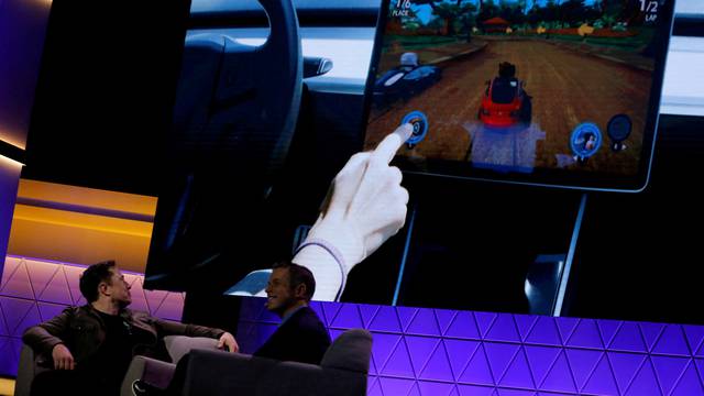 FILE PHOTO: Elon Musk watches a clip of a videogame in a Tesla Model 3 vehicle during a gaming convention in LA, June 2019.