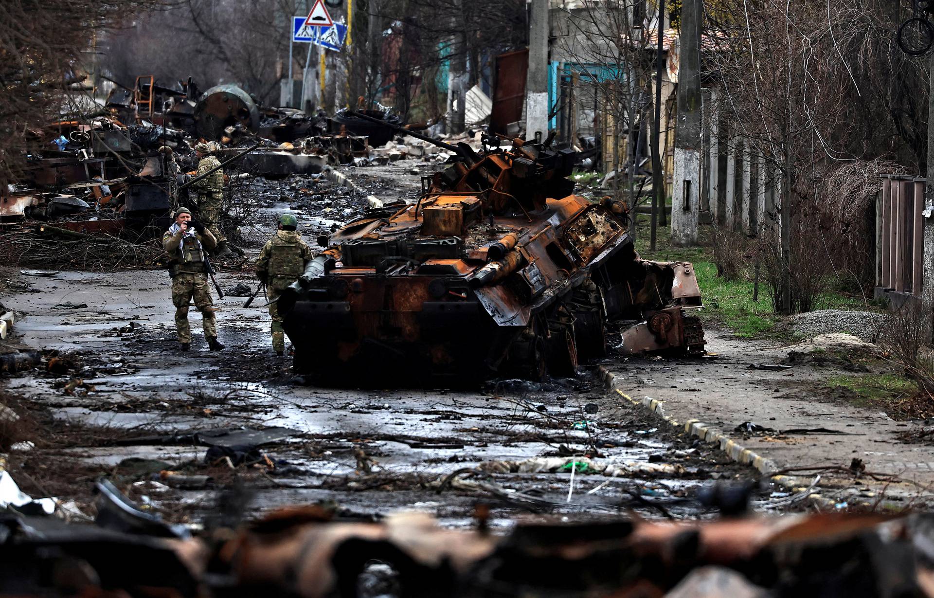 A soldier takes a photograph of his comrade as he poses beside a destroyed Russian tank and armoured vehicles, amid Russia's invasion on Ukraine in Bucha, in Kyiv region