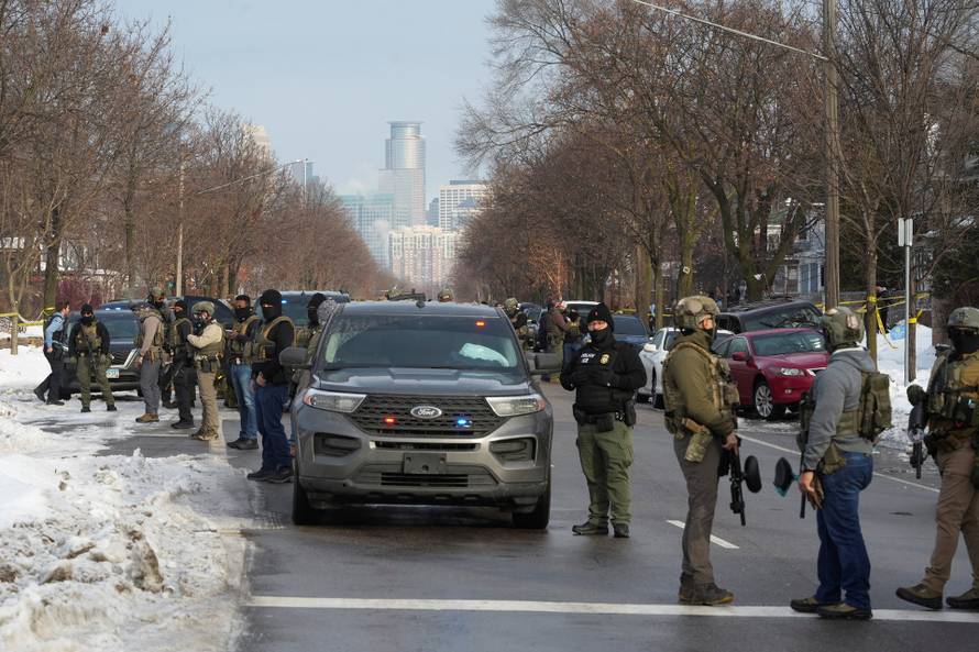 Members of U.S. Immigration and Customs Enforcement (ICE) stand guard after a driver of a vehicle was shot in Minneapolis