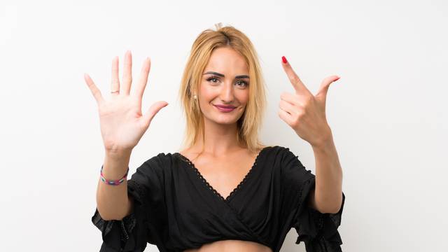 Young blonde woman over isolated white wall counting seven with fingers